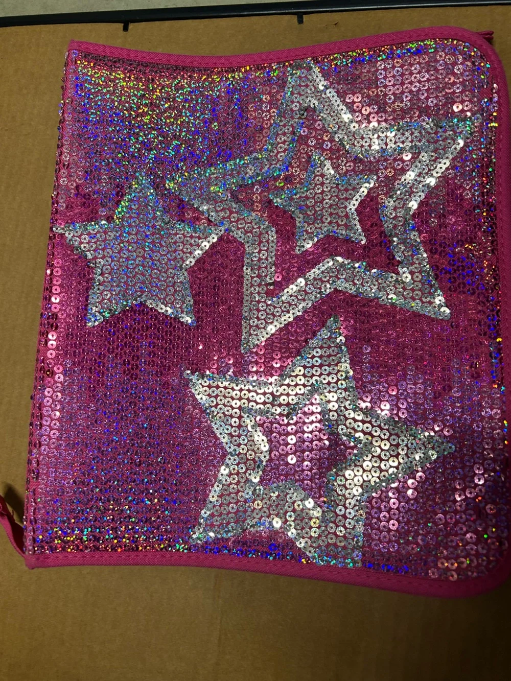 Hot pink, 3 ring binder notebook that zips up and has sequins on the front.